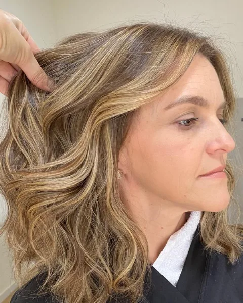 A Lari ajusta as ondas de uma cliente durante a finalização, no studio